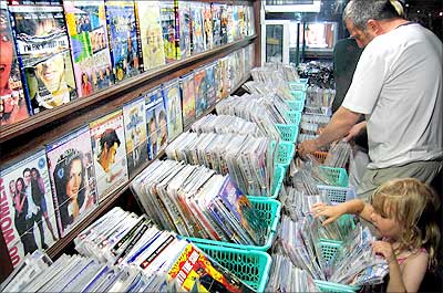 Tourists go through an assortment of pirated music CDs and DVDs
