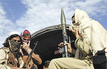 Pakistani Taliban fighters sit with their weapons on the back of a truck in Buner