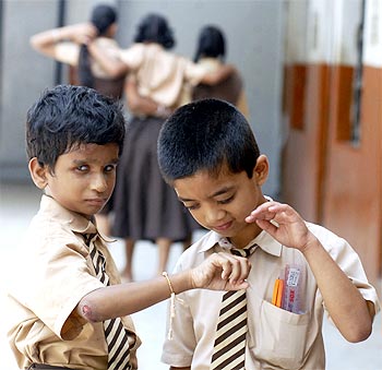 A visually-impaired schoolboys play with a rakhi tied onto the wrist of one of the boys inside their school in Hyderabad