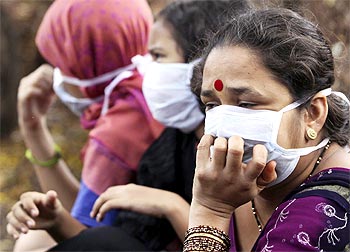 Women wearing masks wait to receive medical attention for suspected H1N1 influenza at a hospital in Pune