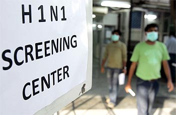People wearing surgical masks walk out of a H1N1 flu screening centre in Ram Manohar Lohia hospital in New Delhi