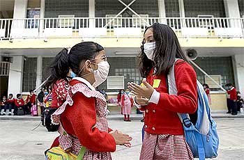 School girls wear protective masks as they stand outside their classrooms at an elementary school in Mexico City