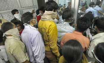 People wearing masks wait in a queue for a H1N1 flu screening at a hospital in New Delhi