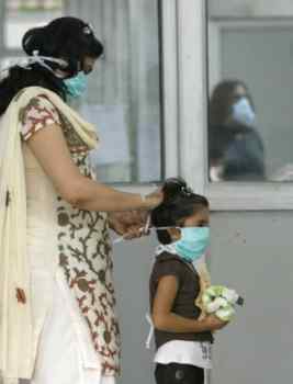 A mother puts on a surgical mask for her daughter as they arrive for a flu screening at Ram Manohar Lohia hospital in New Delhi