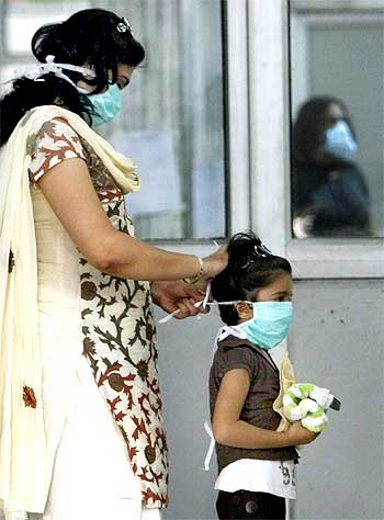 A mother puts on a surgical mask for her daughter as they arrive for a H1N1 flu screening at Ram Manohar Lohia hospital in New Delhi