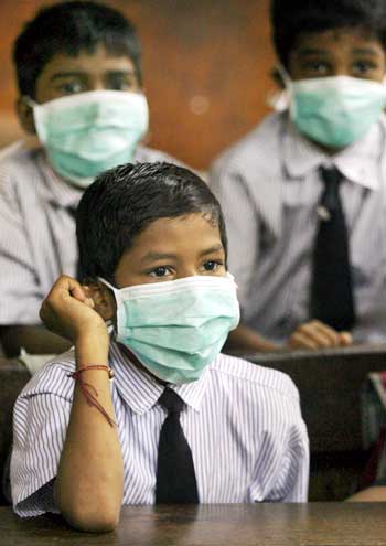 Children wearing masks sit in a classroom at a school in Mumbai