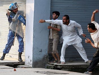 Demonstrators throw stones at a Rapid Action Force soldier during a protest in Jammu against the government's decision not to give forest land to a trust that runs Amarnath cave shrine