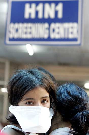 A woman carries her daughter as they wait for a H1N1 flu screening at a hospital in New Delhi