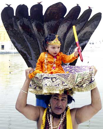 A devotee carries a child dressed as Krishna in a basket at the Durgiana temple on the eve of Janamashtmi in Amritsar