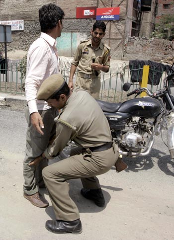 A policeman searches a youth ahead of Independence Day celebrations in Srinagar
