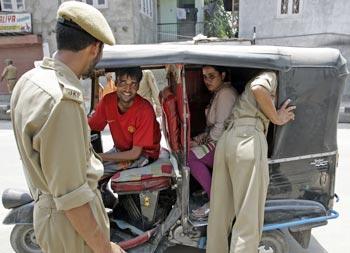 Policemen inspect a vehicle ahead of Independence Day celebrations in Srinagar