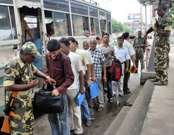 A policeman checks the bag of a bus passenger as others wait in a queue for their turn in Guwahati
