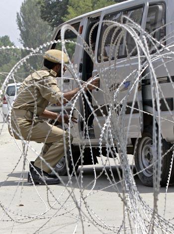 A policeman inspects a car ahead of Independence Day celebrations in Srinagar