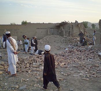 Villagers gather at a damaged house after a missile strike in Dandi Darpakheil village