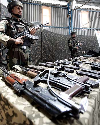 A soldier stands guard near seized arms and ammunition at an Army garrison in Kupwara, Kashmir