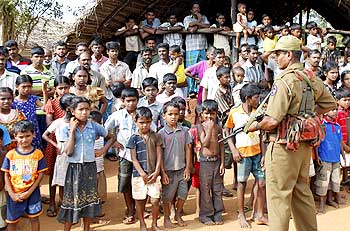 A Sri Lankan policeman stands guard over displaced Tamil civilians.