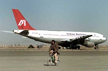 An Afghan on his bicycle passes the hijacked Indian Airlines plane
