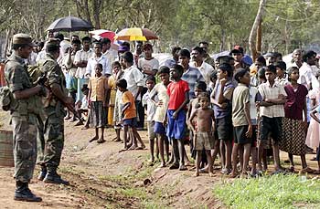 Soldiers stand guard near IDPs at the Vavuniya camp