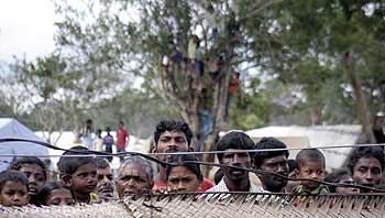 IDPs look over a fence as they stand inside a camp in Vavuniya
