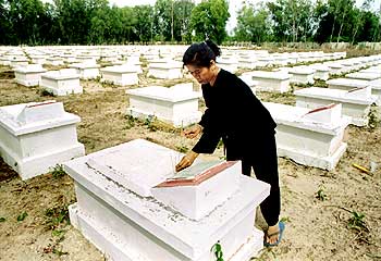 Former National Liberation Front (Viet Cong) guerilla Do Thi Hanh places incense on the grave of her brother Do Van Boi at a cemetry for war heros