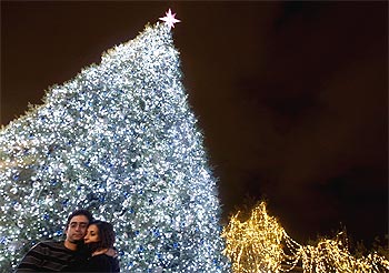 A couple hugs in front of a Christmas tree during a lighting ceremony at central Syntagma square in Athens