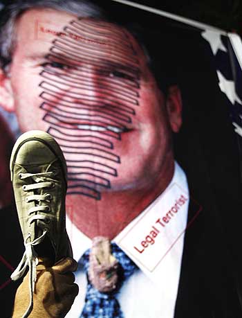 Jordanians from opposition parties hold their shoes beside a poster of George Bush