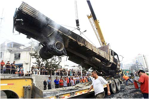 A truck, which was destroyed in Sunday's riot, is hoisted