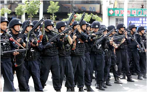 Chinese riot police get into position as Uighur protesters gather during a demonstration