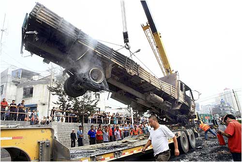 A truck which was destroyed in Sunday's riot is hoisted in Urumqi, Xinjiang Uigur Autonomous Region.