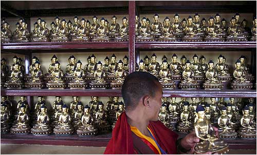A monk adjusts Buddha statuettes at a monastery in Kathmandu