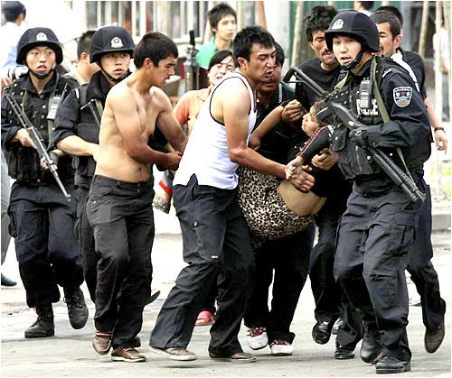 Policemen carry a woman who had fainted on a street in Urumqi