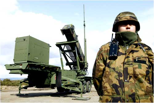 A soldier stands next to a Japanese Self-Defence Force Patriot Advanced Capability-3 (PAC-3) missile unit
