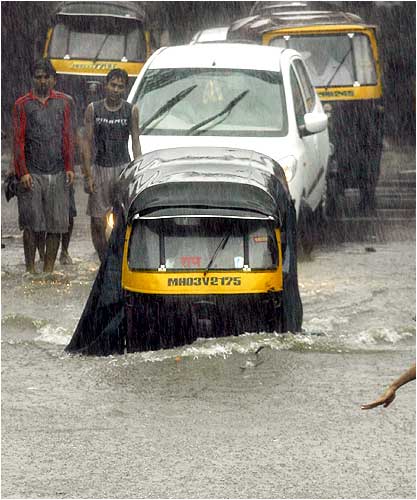 An autorickshaw moves through a flooded road