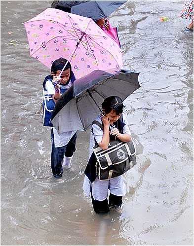 School kids walk through a flooded street