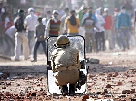 A policeman faces protesters in Srinagar