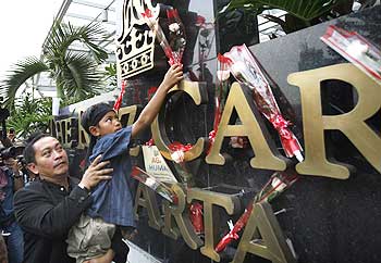 A boy places a flower in front of the Ritz-Carlton hotel in memory of those killed by a bomb blast, in Jakarta