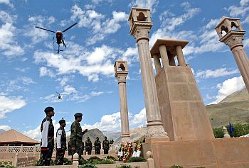 Indian army helicopters fly past as a senior army officer pays homage at war memorial during Vijay Diwas in Drass