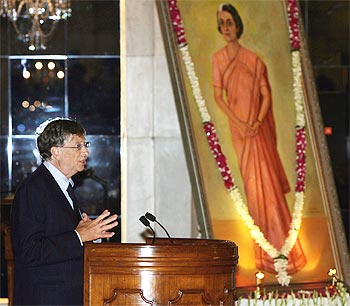 Bill Gates speaks beside a portrait of India's former prime minister Indira Gandhi during the conferment ceremony
