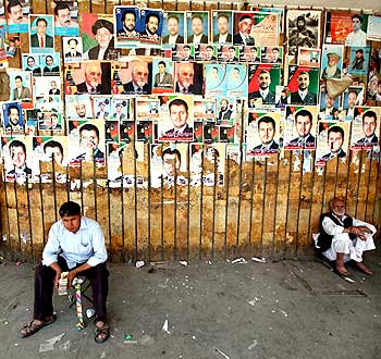 A man waits under posters of presidential candidates in Afghanistan's upcoming election in Kabul.