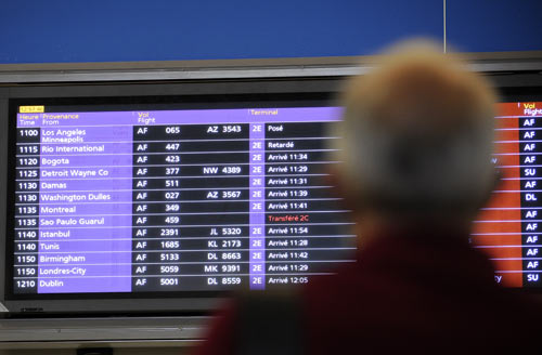 A man looks up at an arrival information sign at terminal 2E at Charles de Gaulle airport near Paris as it advises a 'delayed' status for flight AF447
