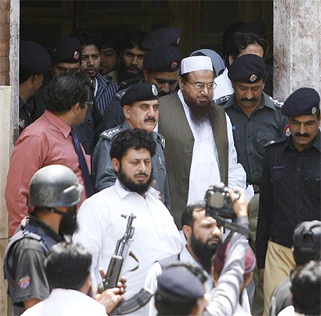 Police escort Hafiz Saeed (in white cap), the head of the banned Jamaat-ud-Dawa and founder of Lashkar-e-Tayiba, as he leaves the Lahore court