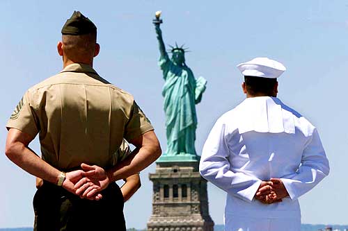 A US Navy sailor stands with a US Marine aboard the USS Iwo Jima as the ship passes the Statue of Liberty in New York Harbour