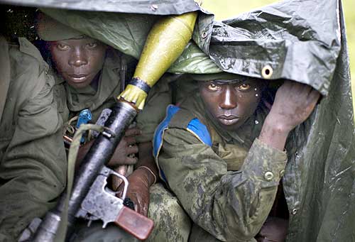 Congolese government soldiers sit in the rain at the frontline near Kibati, north of Goma in eastern Congo