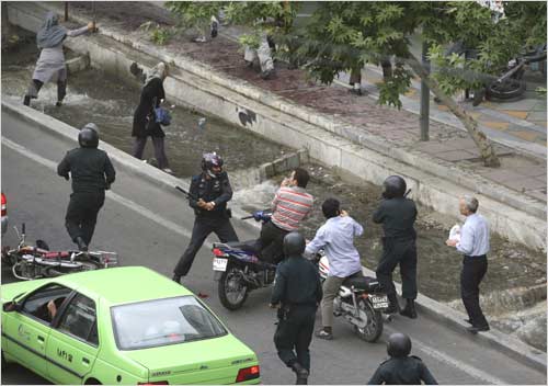 A riot policeman hits a motorcyclist with a baton during the protest
