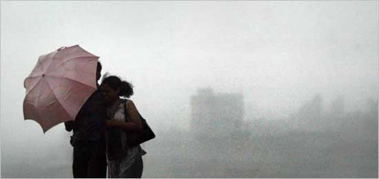 An Indian couple stands in the rain at a waterfront in Bombay June 15, 2004. India's south-west monsoon arrived on schedule in Bombay, the country's financial capital.