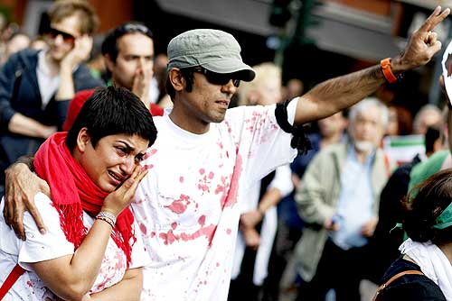 A protester cries as another flashes a victory sign during a demonstration in support of the Iranian opposition
