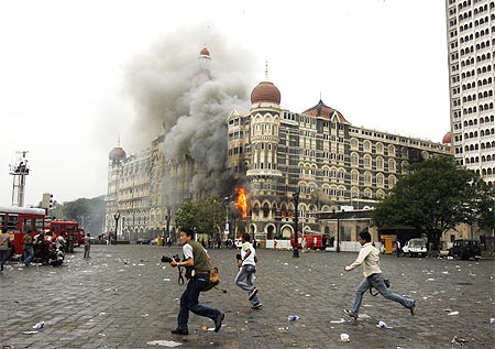 Photographers run past the burning Taj Mahal hotel in Mumbai, November 29, 2008