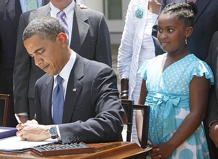 Obama signs the Family Smoking Prevention and Tobacco Control Act. Watching Obama is Sarah Louise Wiggins, 9, of the Campaign for Tobacco Free Kids.