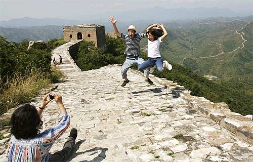 A Chinese family jump as they pose for a photo at the Great Wall of China