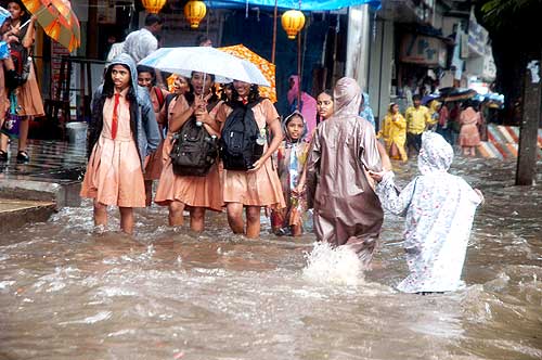 School children make their way through the flooded pavement